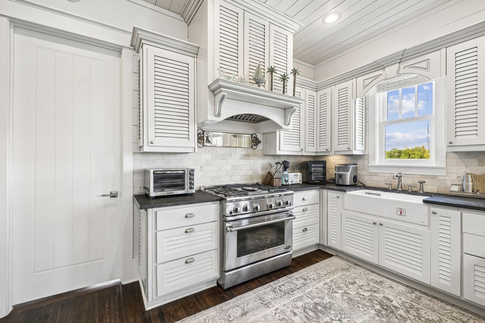 Your gourmet kitchen features professional-grade appliances, elegant white cabinetry, and gleaming countertops—perfect for whipping up delicious meals while natural light streams through the window.