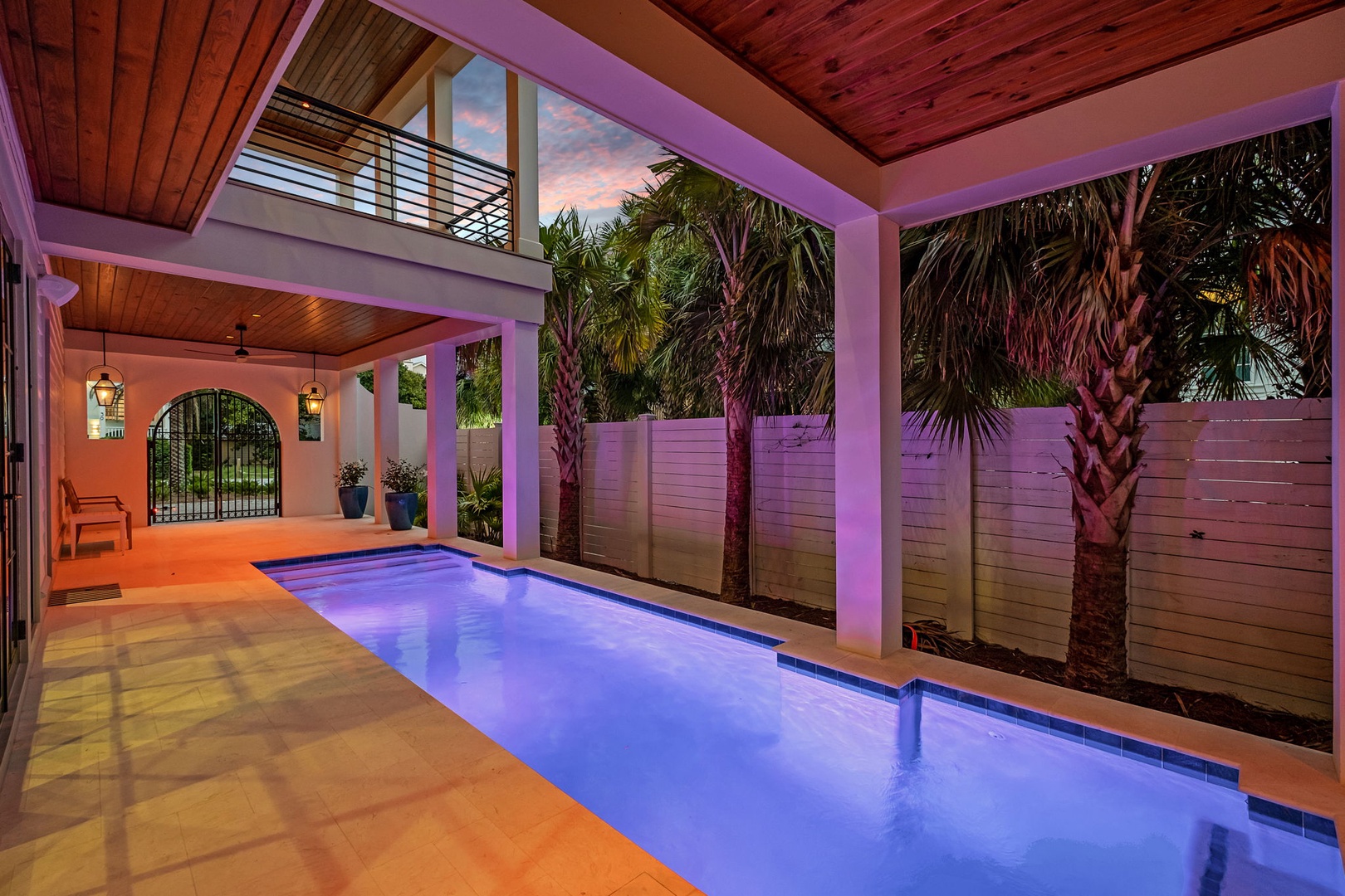 Dive into your private tropical oasis, where the pool's blue glow creates perfect evening ambiance beneath soaring wood ceilings and swaying palms.