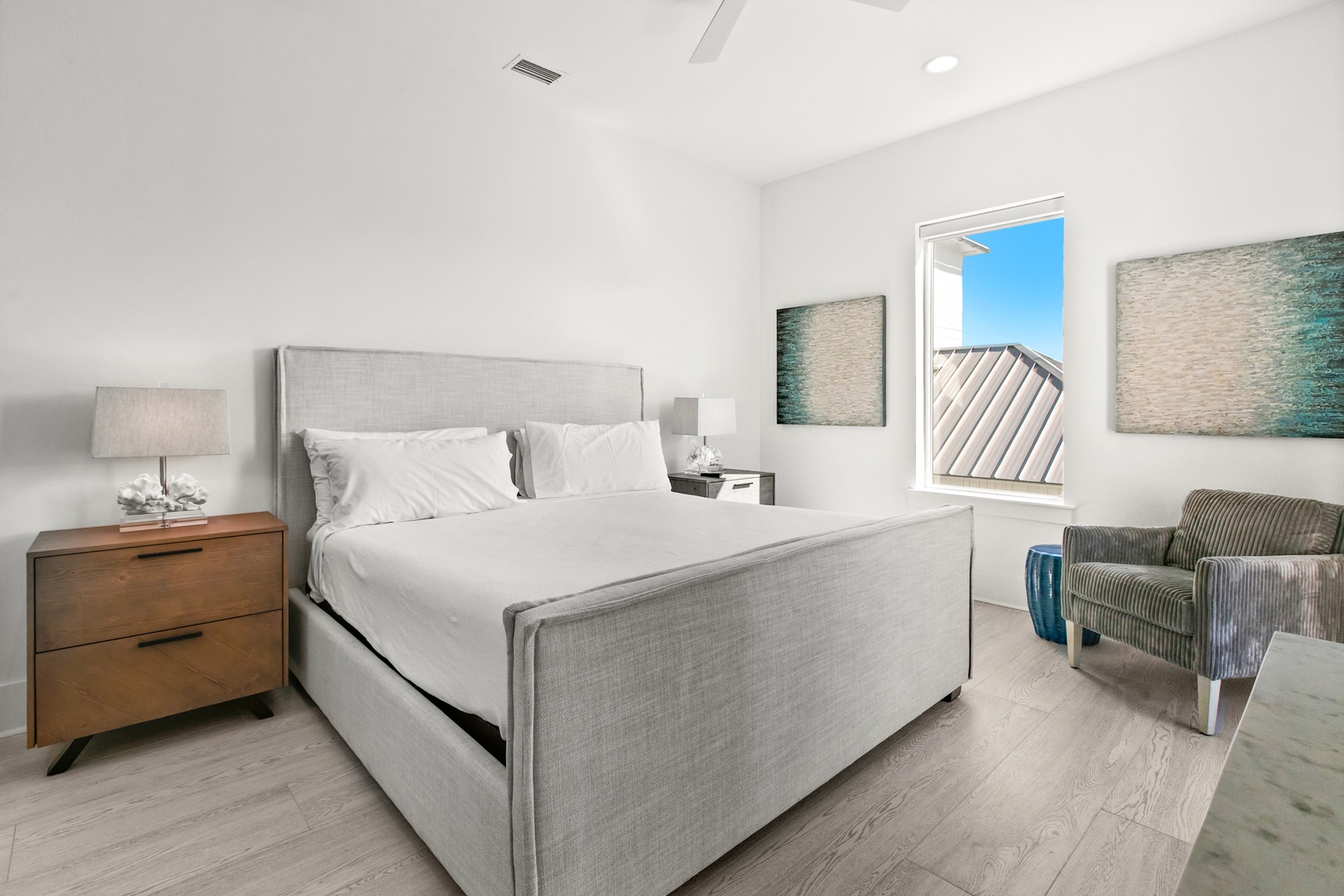 Step into your bright, serene bedroom where calming coastal tones and crisp white linens await. The plush bed and cozy reading chair create the perfect retreat after a day of exploration.