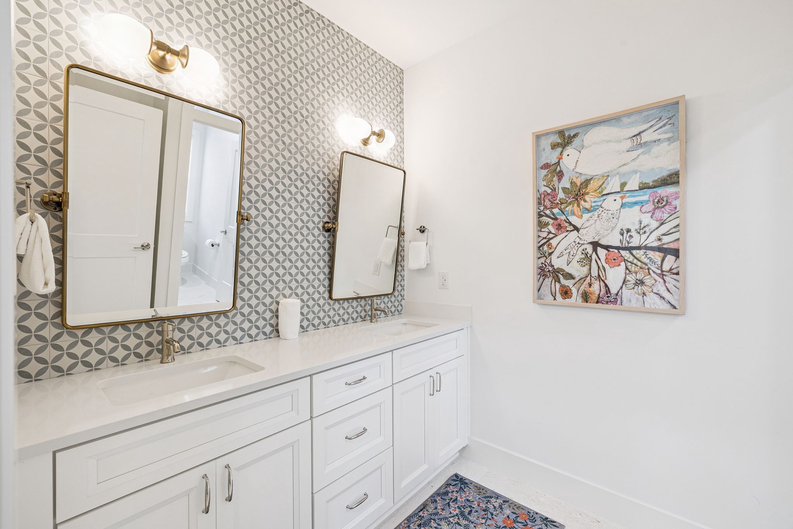 Your elegant en-suite features dual vanities with geometric tile accents and warm brass fixtures for a luxurious morning routine.