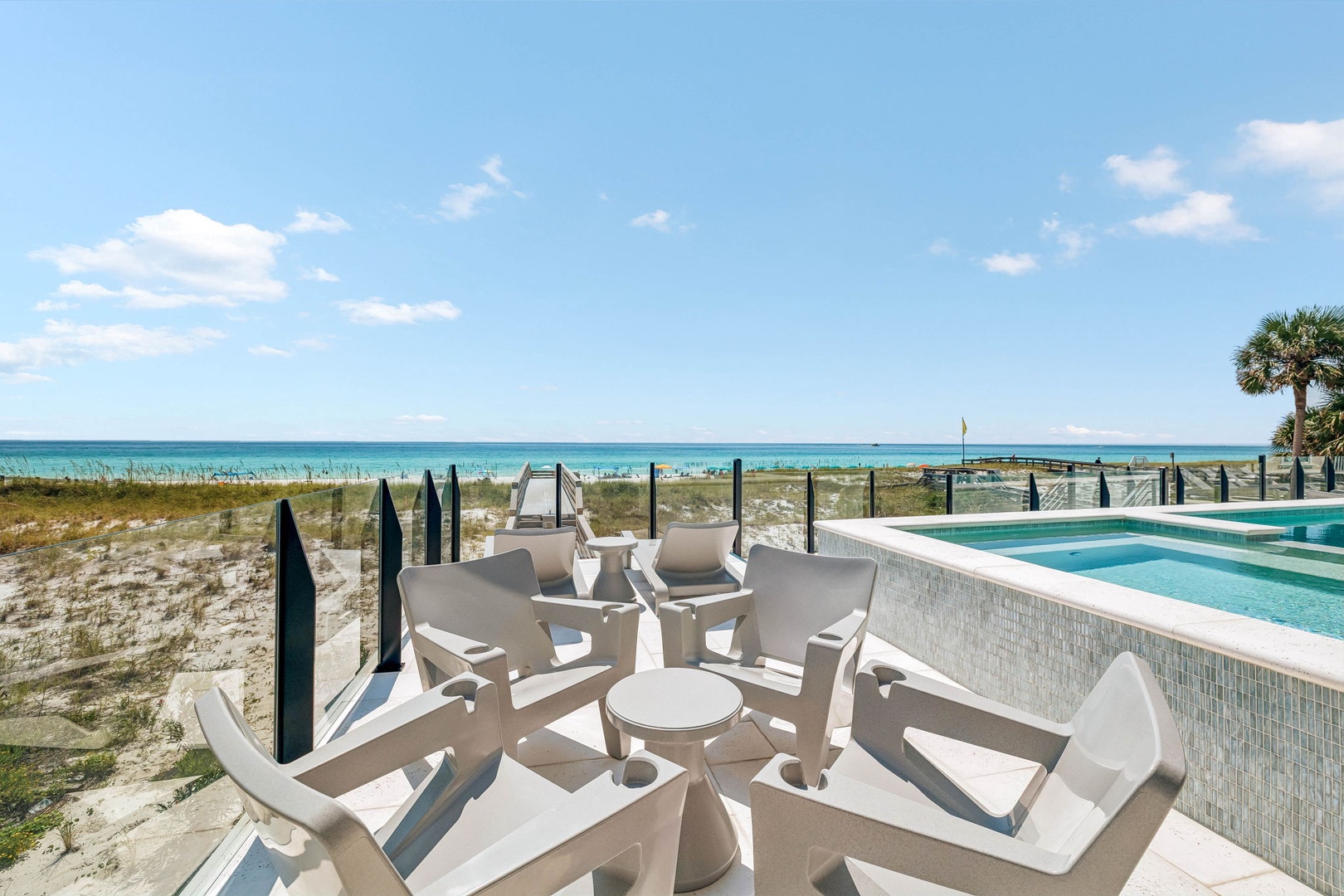 Your private beachfront terrace awaits, where white lounge chairs and a sparkling pool meet sugar-soft sand and turquoise waters—pure coastal paradise at your doorstep.