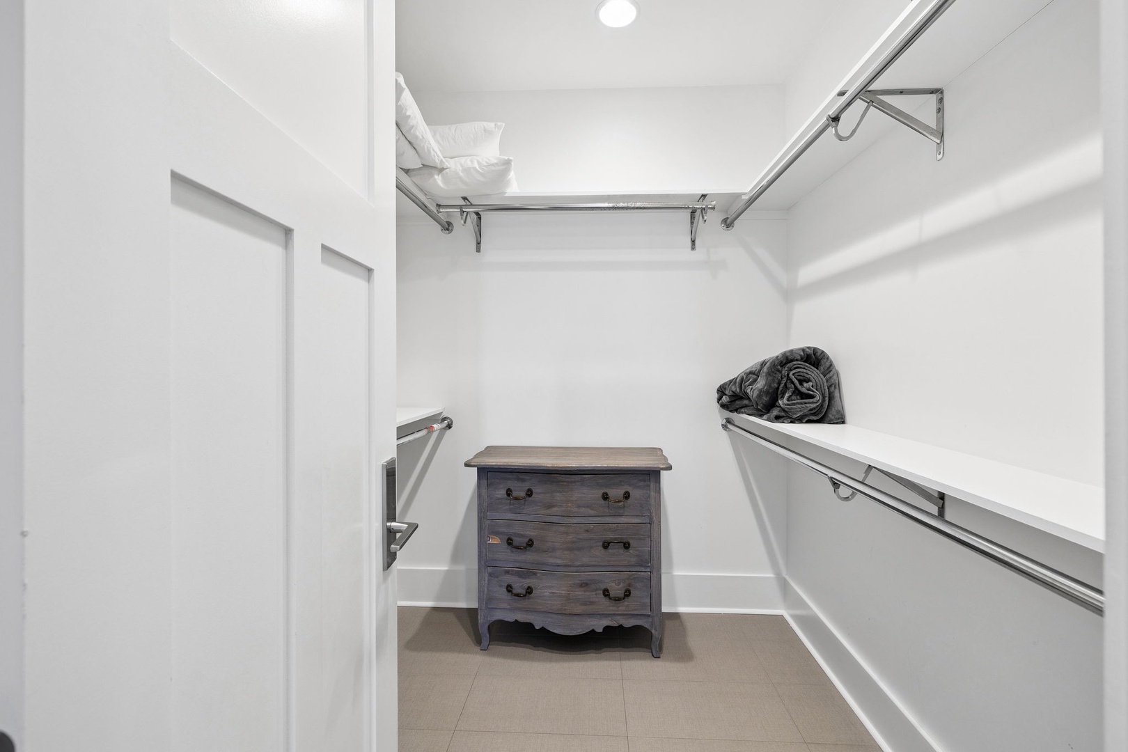 Store your belongings in this spacious walk-in closet with ample hanging space and charming vintage dresser for organized comfort.