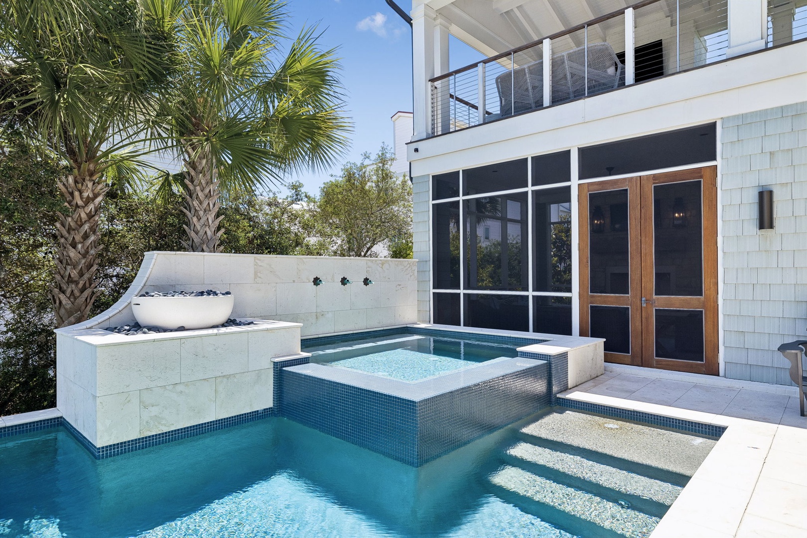 Dive into relaxation in your private pool, complete with an elevated hot tub and a modern water feature. Palm trees and a spacious deck set the stage for unforgettable sunny days.