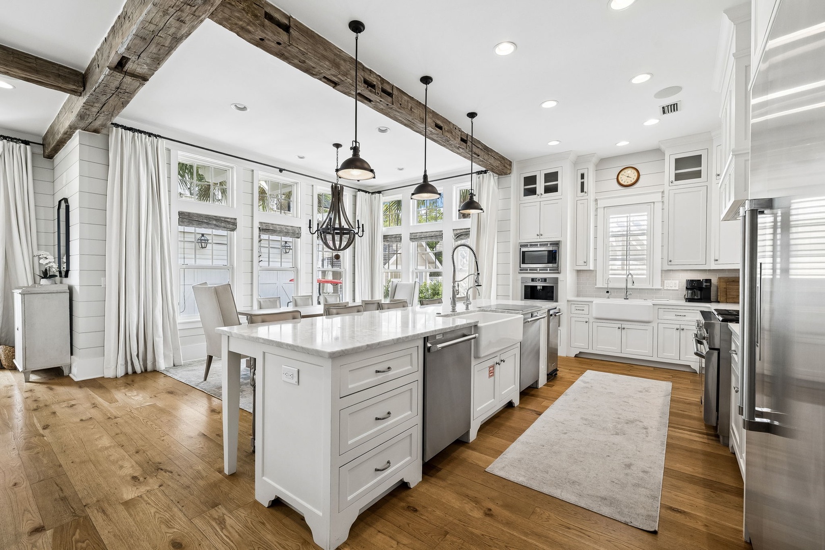 Step into your dream kitchen, where soaring ceilings with rustic wooden beams meet elegant white cabinetry. Natural light pours through tall windows, illuminating a spacious island perfect for cooking and gathering with loved ones.