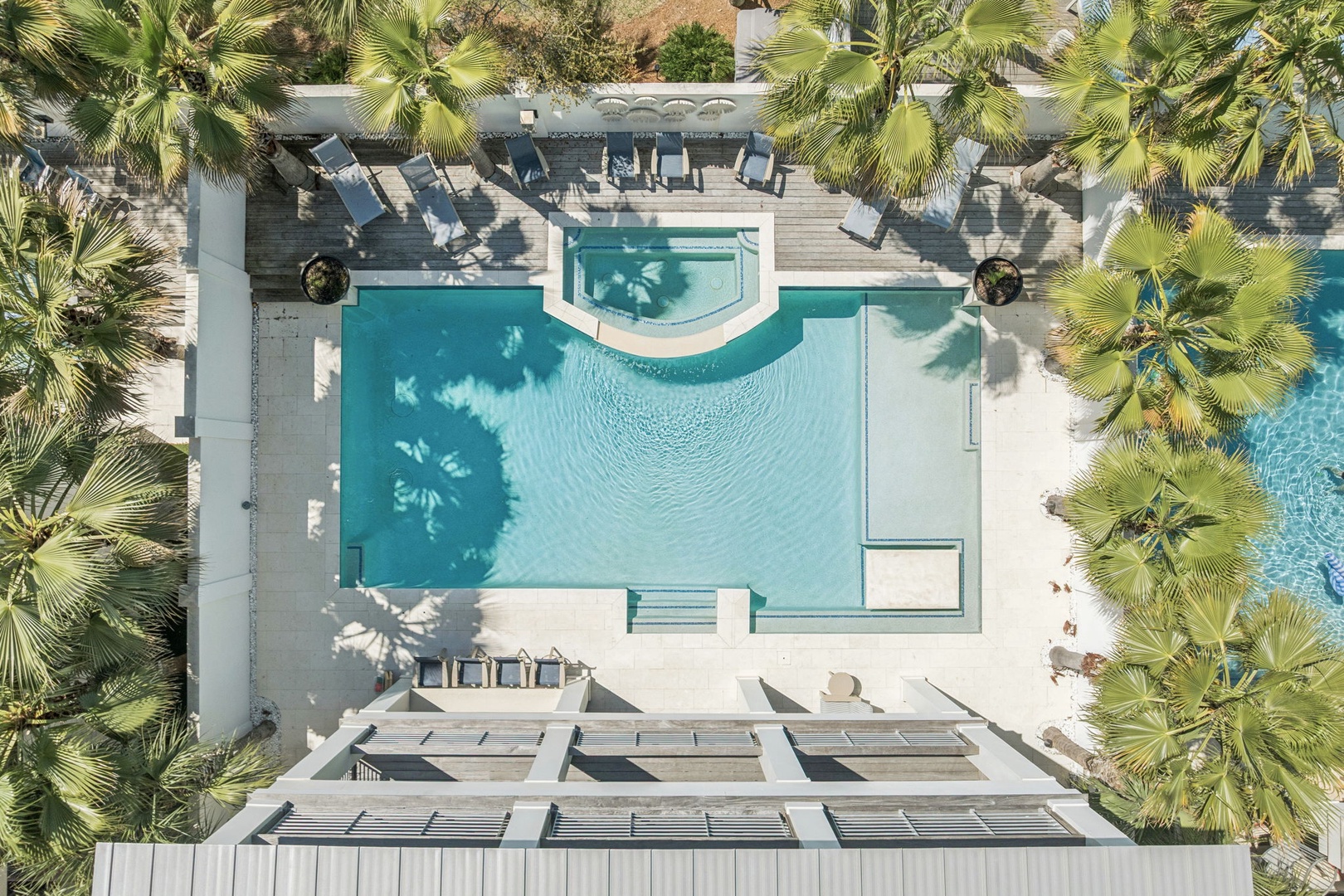 Aerial view of the resort's stunning pool area surrounded by tropical palm trees and modern amenities.