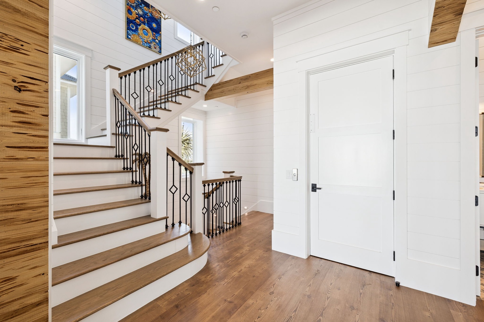 Step into your elegant entryway where rich hardwood floors meet soaring ceilings and a stunning staircase with decorative iron railings welcomes you home.