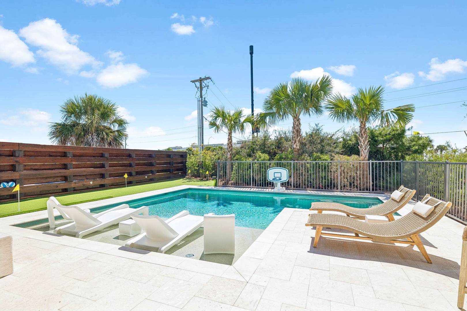 Sunny poolside retreat framed by swaying palms and lush greenery. Lounge on comfortable sunbeds, challenge friends to a basketball game, or simply unwind by the sparkling water in your own private oasis.