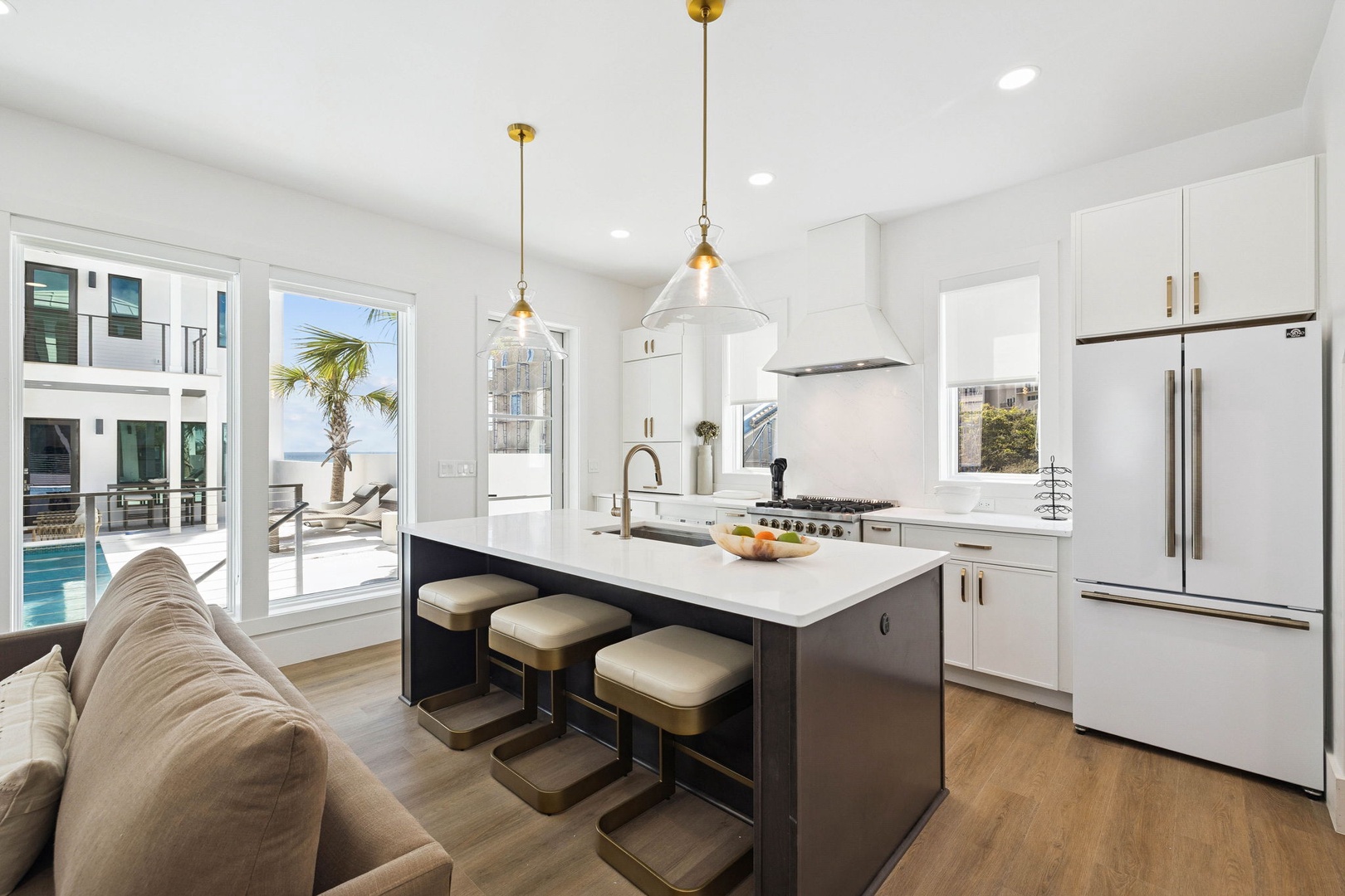Your modern kitchen invites culinary adventures with its sleek island seating and coastal views just beyond the glass doors, where pool days and ocean breezes await.