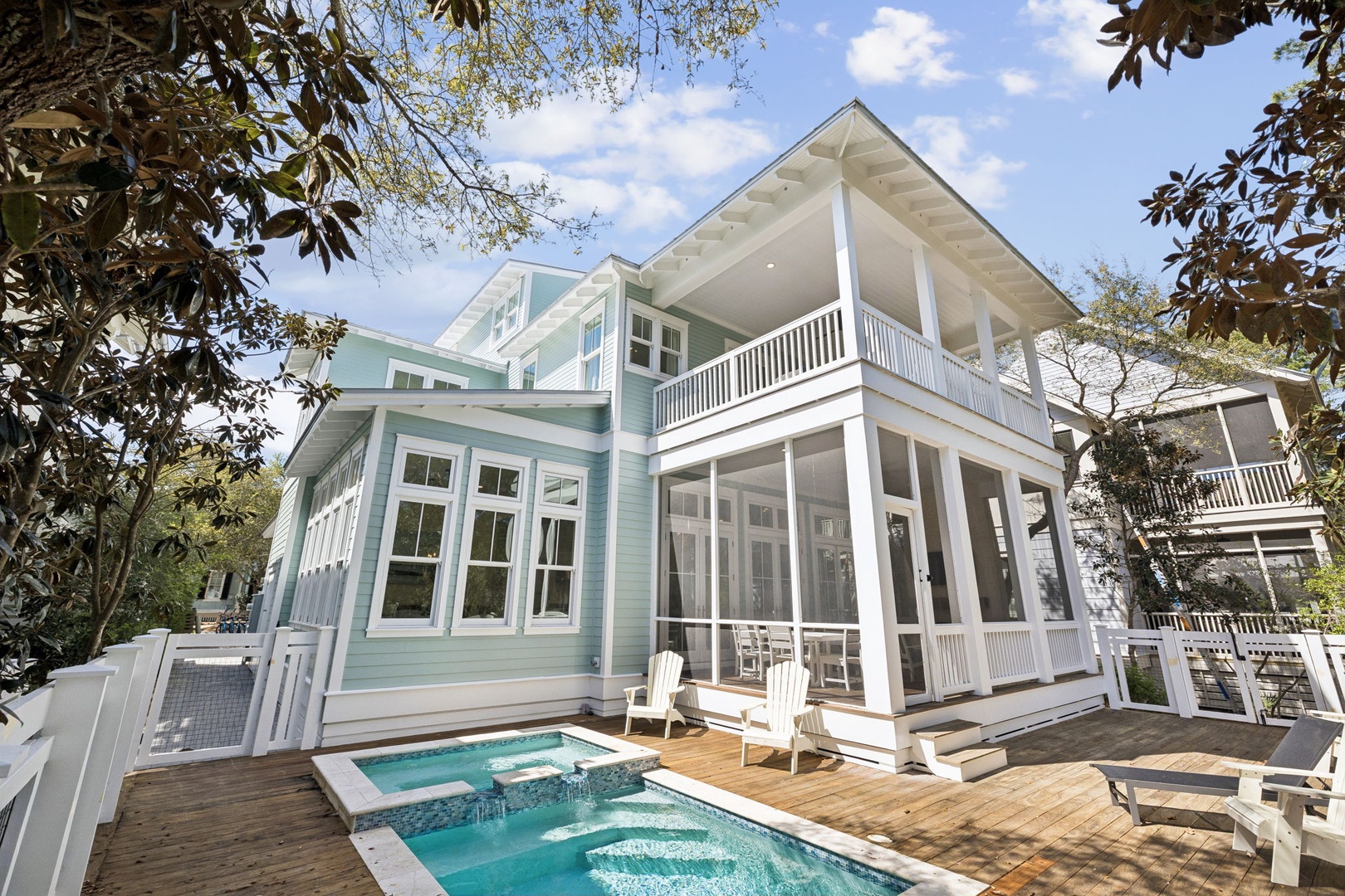 Charming coastal home with private pool and covered porches, nestled among mature trees in a peaceful neighborhood setting.