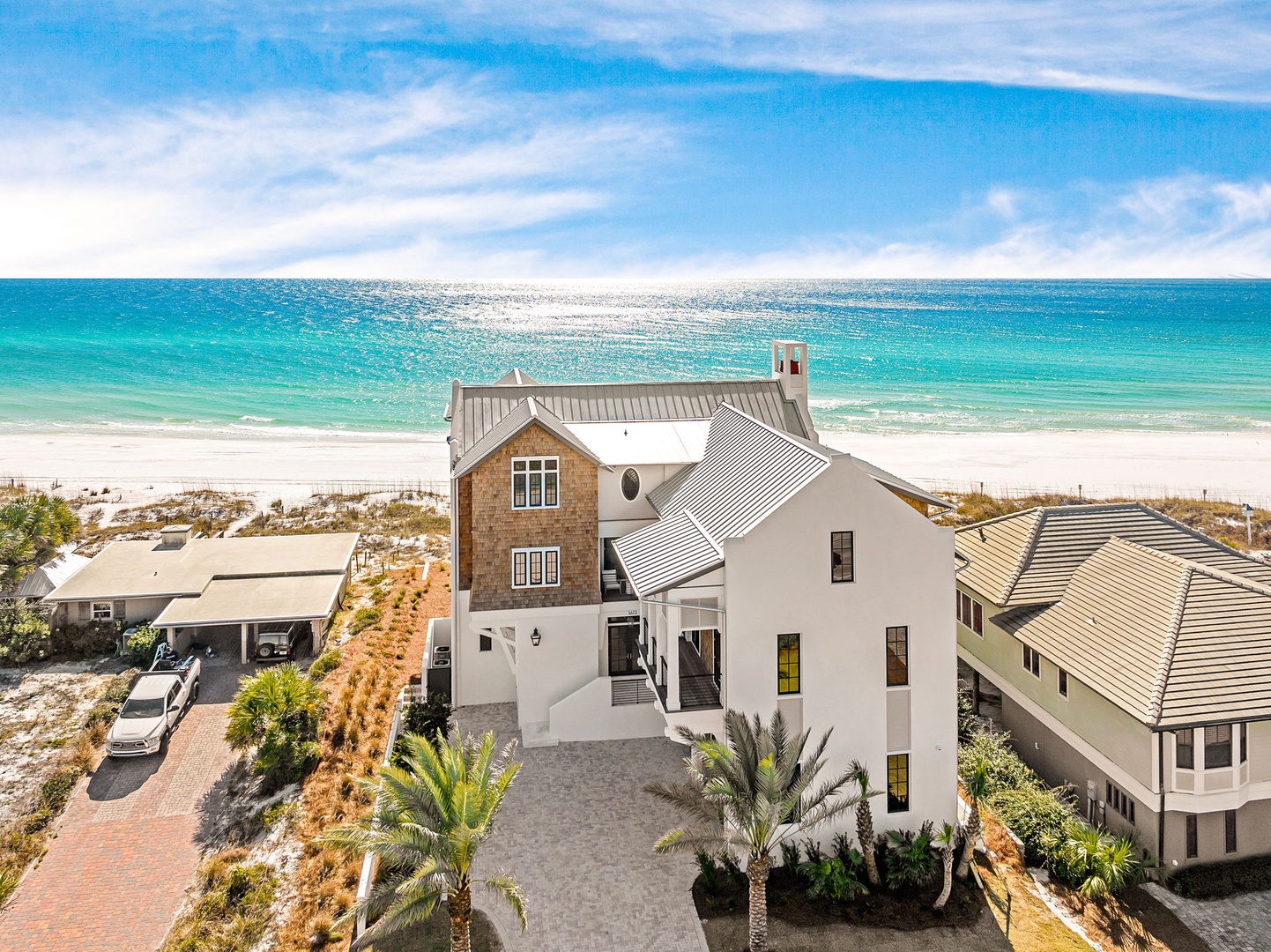 Stunning beachfront property showcases modern coastal architecture with pristine white sand beach and turquoise waters just steps away.