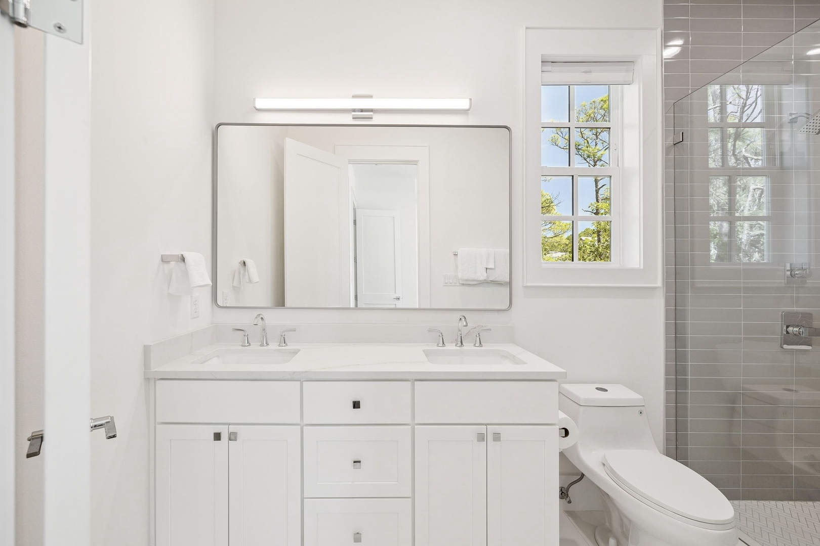 Your private bathroom features dual sinks, elegant marble countertops, and a spacious walk-in shower with contemporary tile work.