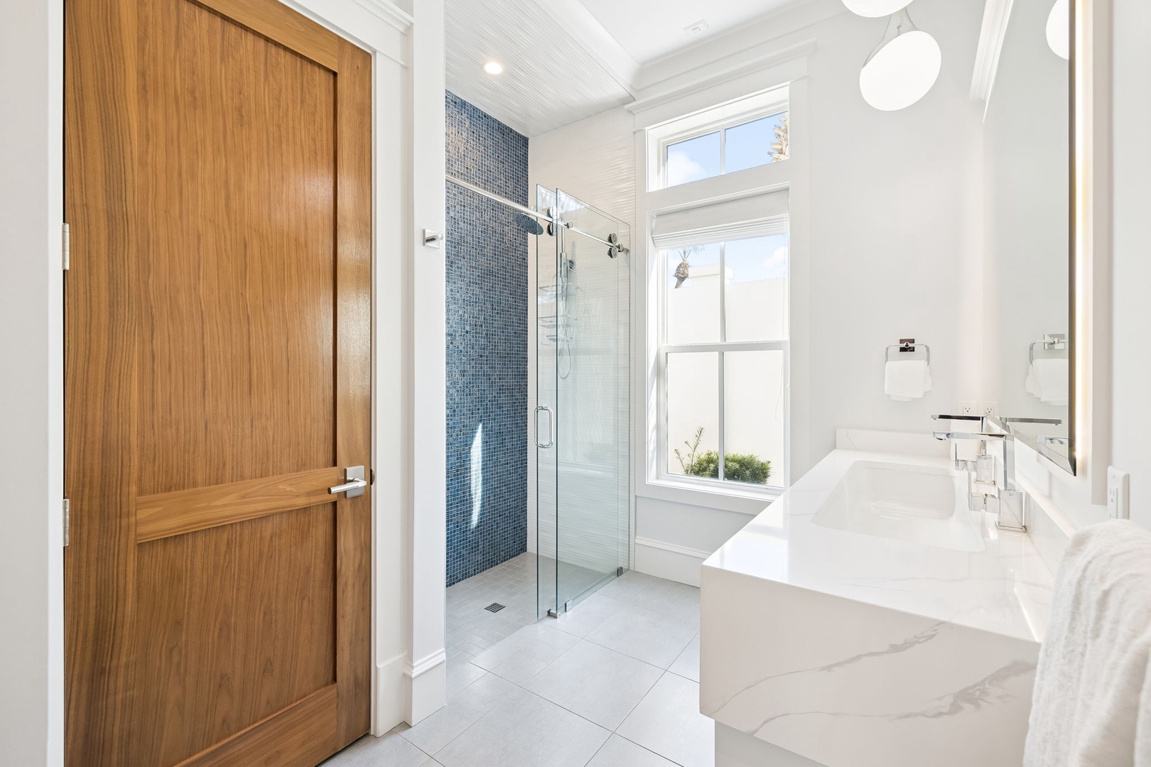 Indulge in your private spa-like retreat with marble counters, a glass-enclosed shower, and elegant fixtures bathed in natural light.