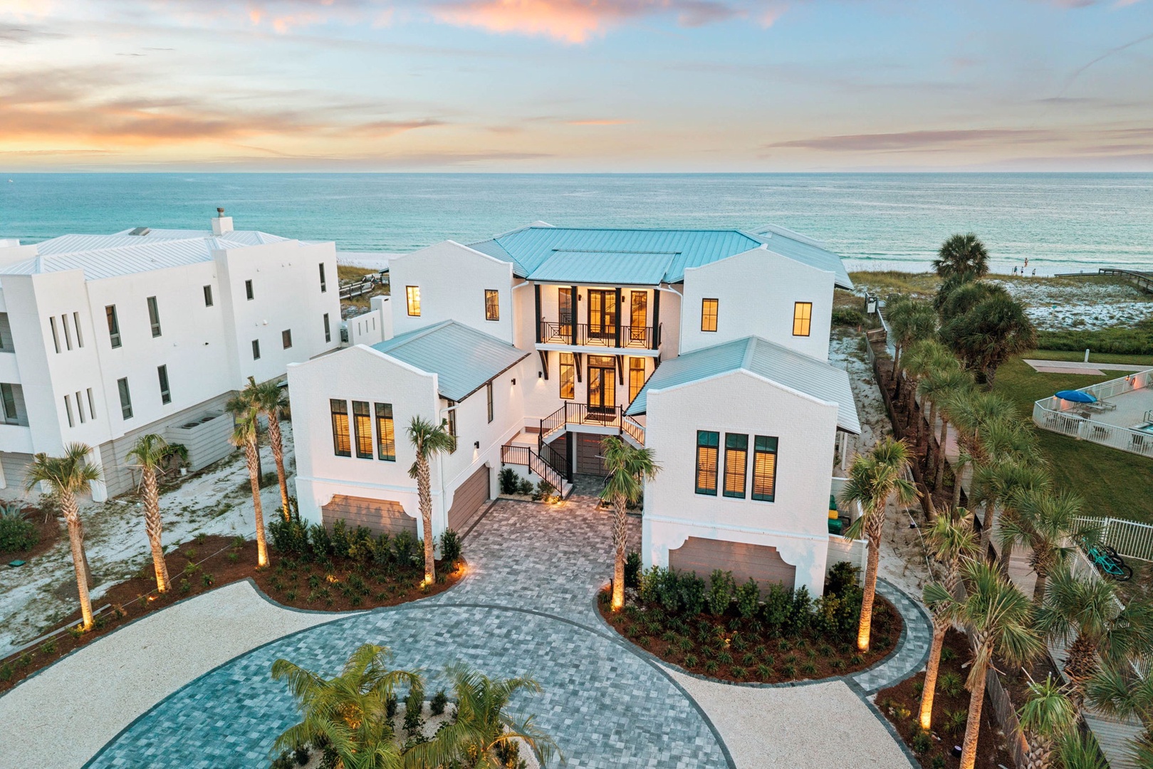 Stunning beachfront property with tropical landscaping and direct ocean access, situated in a pristine coastal setting at sunset.