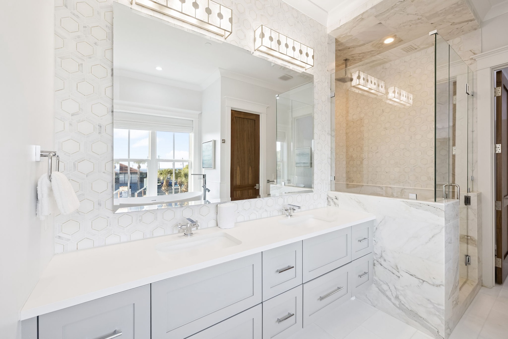 Indulge in this spa-like master bathroom with dual vanities, marble countertops, and elegant lighting for your morning routine.