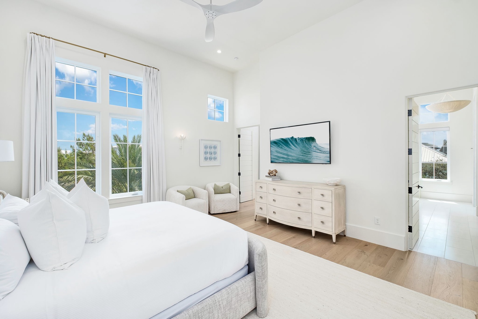 Drift off in your serene bedroom, where tropical breezes flow through expansive windows and soft linens invite peaceful slumber. High ceilings and elegant furnishings create your private coastal sanctuary.