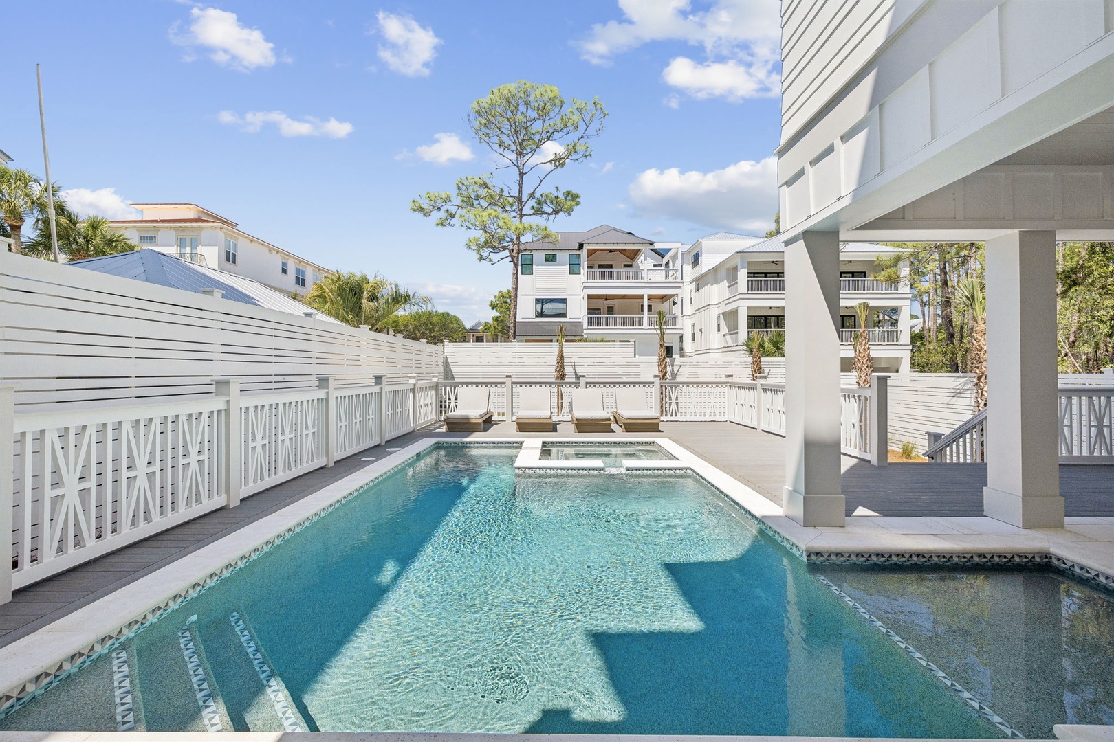 Dive into your private oasis where crystal-clear waters sparkle under Florida sunshine, surrounded by elegant white railings and tropical palms.