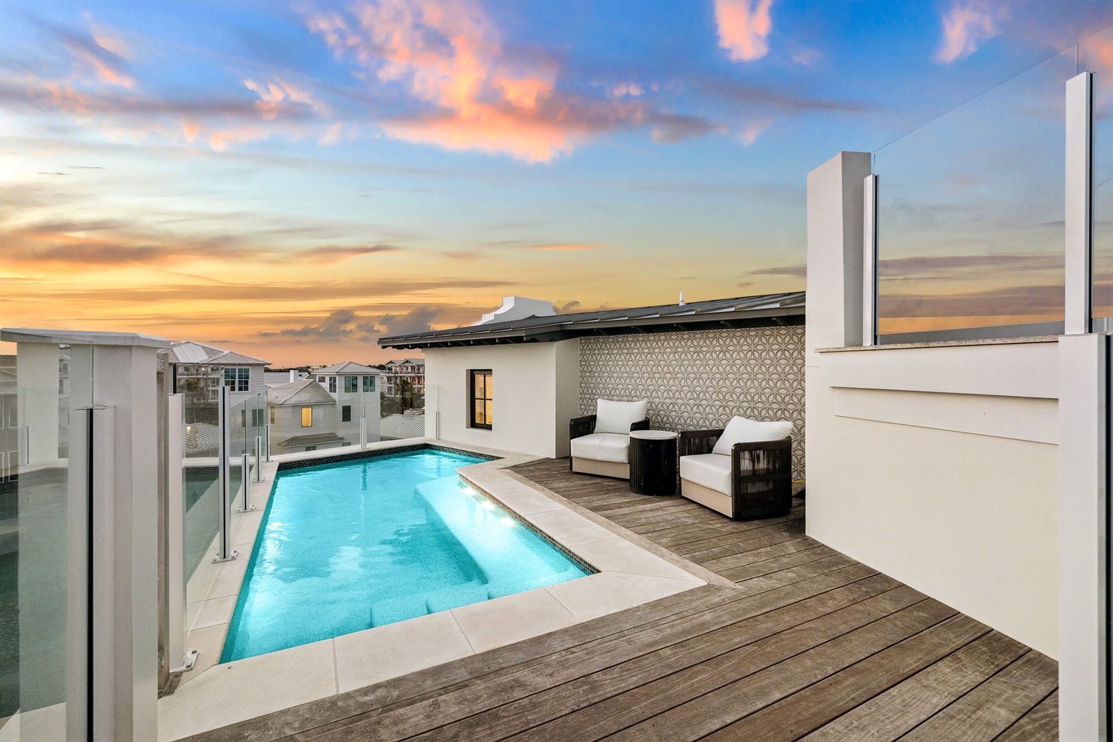 A rooftop deck area with pool, outdoor seating, and contemporary architectural elements, captured during golden hour.