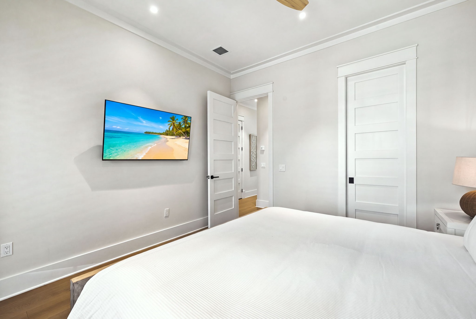 Sink into crisp white linens in your peaceful bedroom, where coastal-inspired touches and a mounted screen create your perfect retreat after a day of exploring.