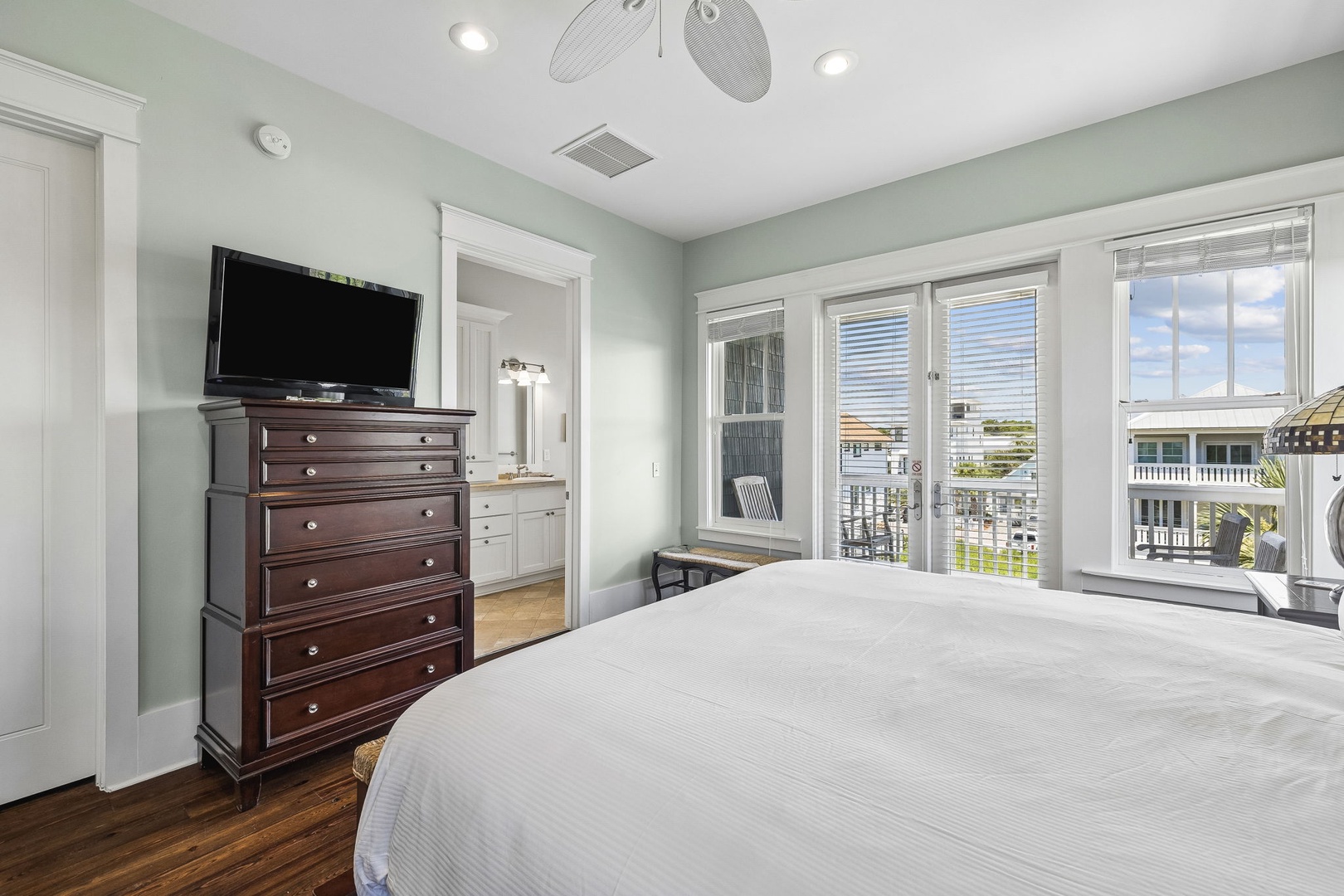 Drift off to sleep in this serene bedroom, where soft coastal hues and gentle ceiling fan breezes meet crisp linens. Your private balcony access opens to lovely neighborhood views, perfect for morning coffee in the fresh air.