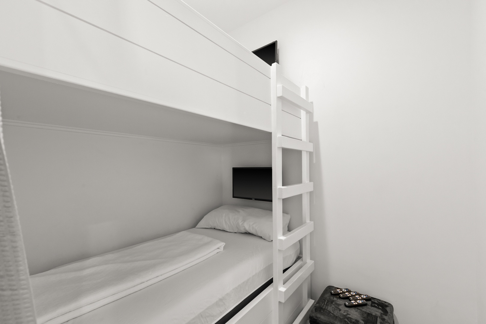 A minimalist bunk bed setup offers your group or family flexible sleeping space, with crisp white linens and a clean, uncluttered design for peaceful rest.