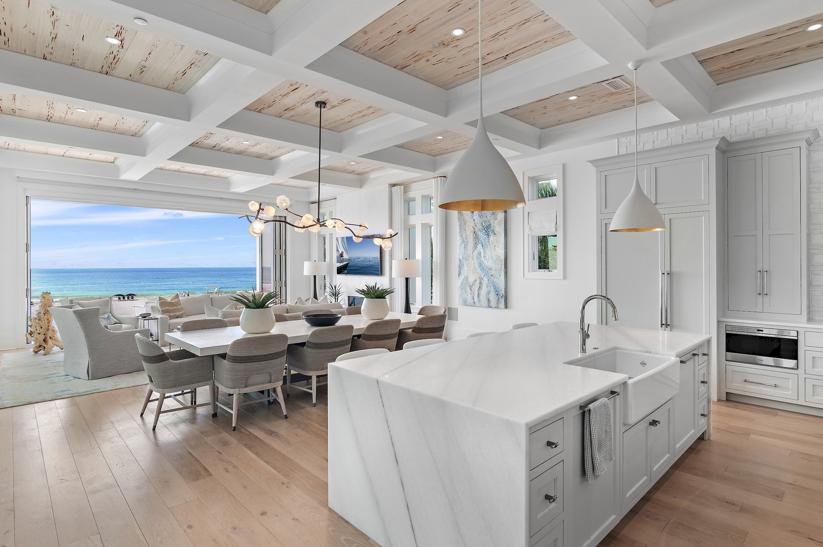Your open-concept kitchen and dining area flows seamlessly toward expansive ocean views. Natural light pours through floor-to-ceiling windows, illuminating the sleek marble island and elegant dining table where every meal becomes a coastal retreat.