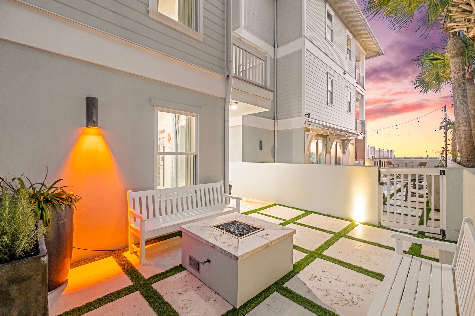This private outdoor patio features modern fire pit seating under a stunning twilight sky. The space blends coastal charm with contemporary design, perfect for unwinding after beach days.