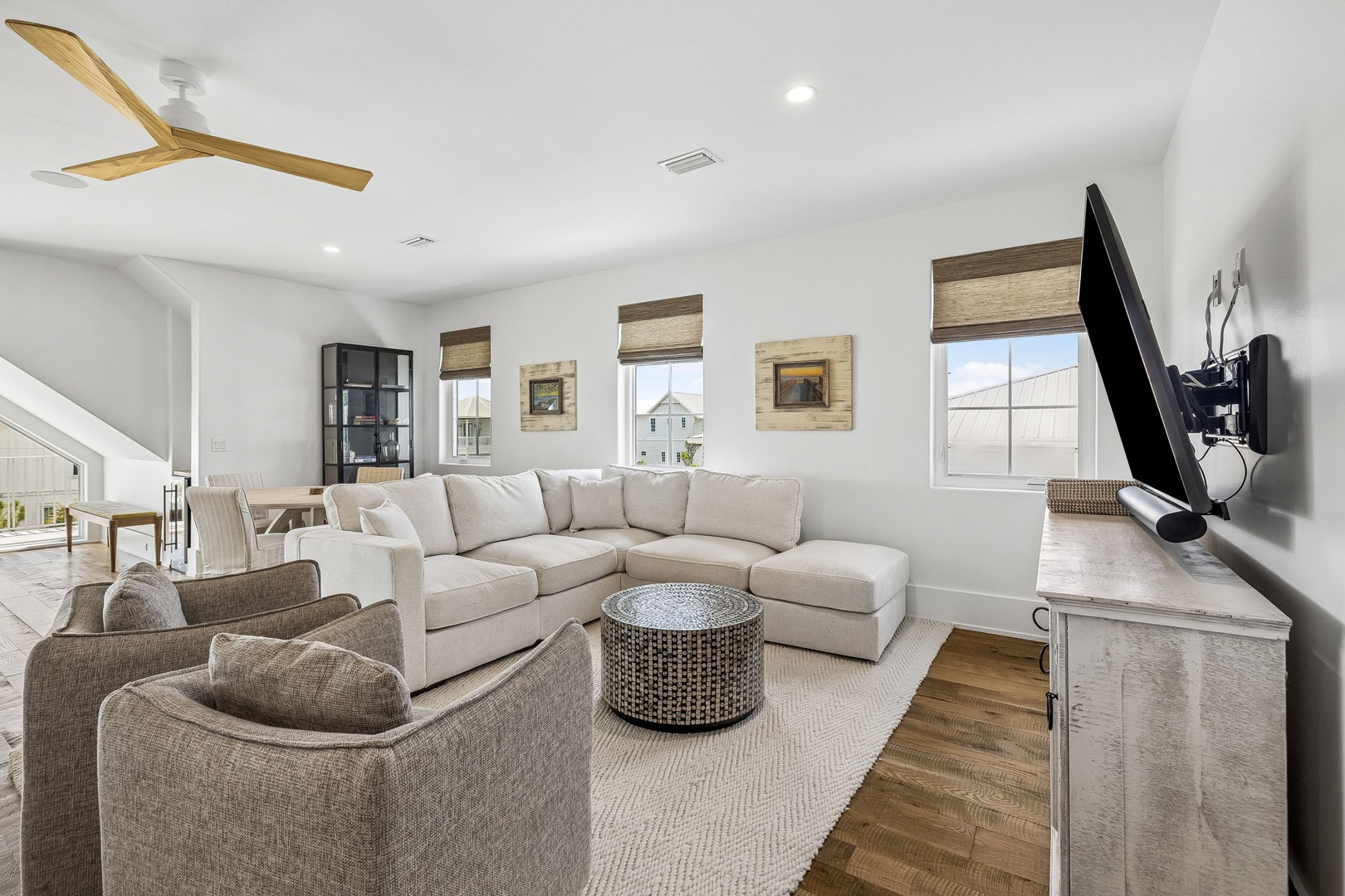 Settle into this bright, airy living space where plush seating and coastal-inspired décor invite you to relax after a day at the beach. Natural light pours through tall windows, and the ceiling fan keeps you cool and comfortable.