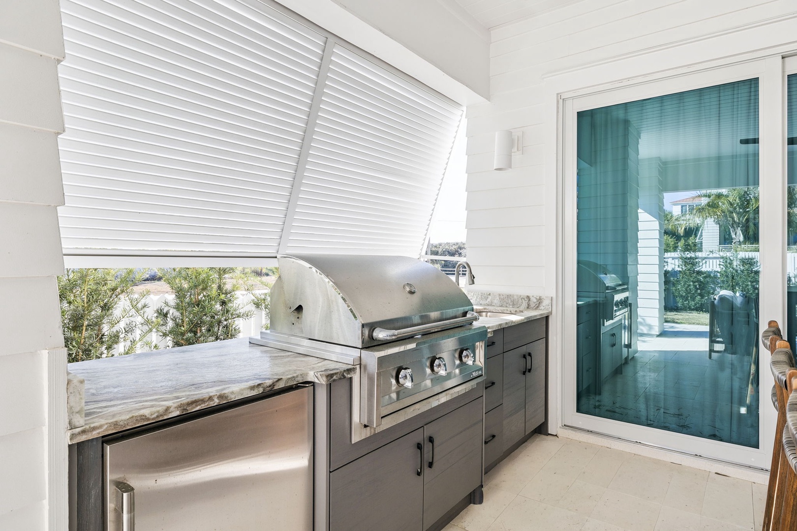 Your private outdoor kitchen awaits with professional-grade grill and sleek countertops, perfect for creating memorable meals while enjoying natural light and garden views.