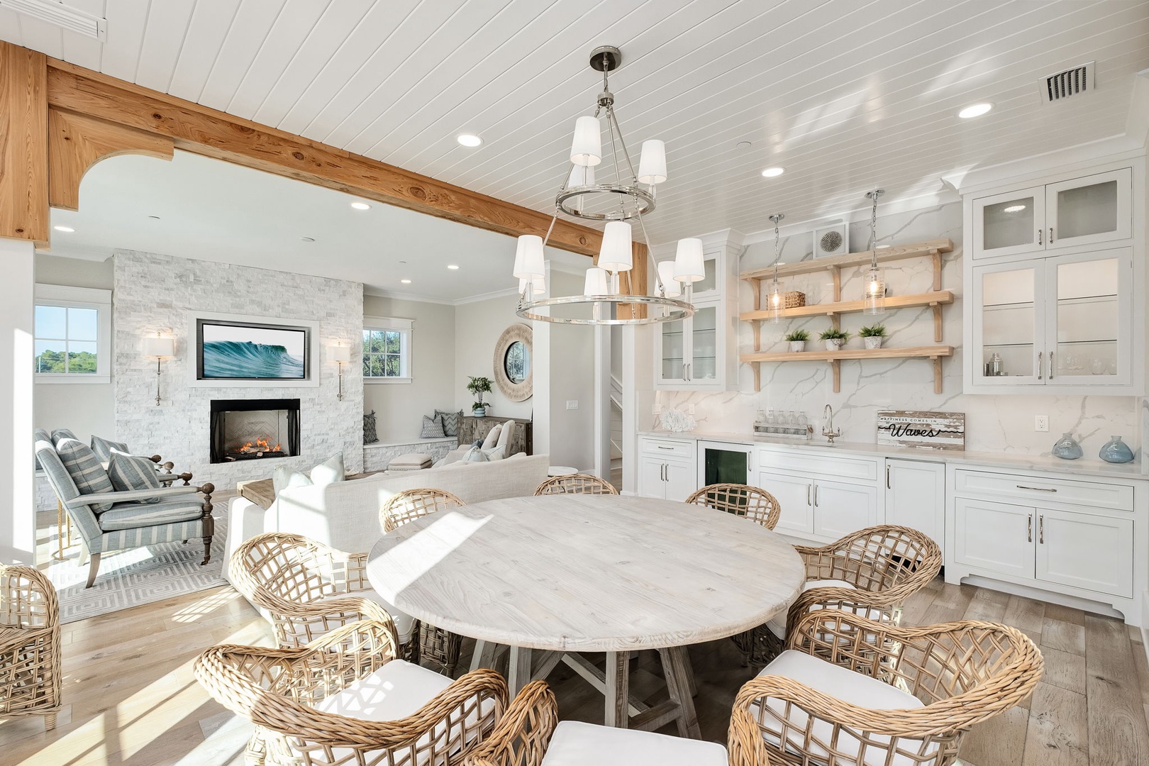 Your open-concept great room flows seamlessly from dining to kitchen to living area, where natural light dances across beautiful wood beams and coastal furnishings.