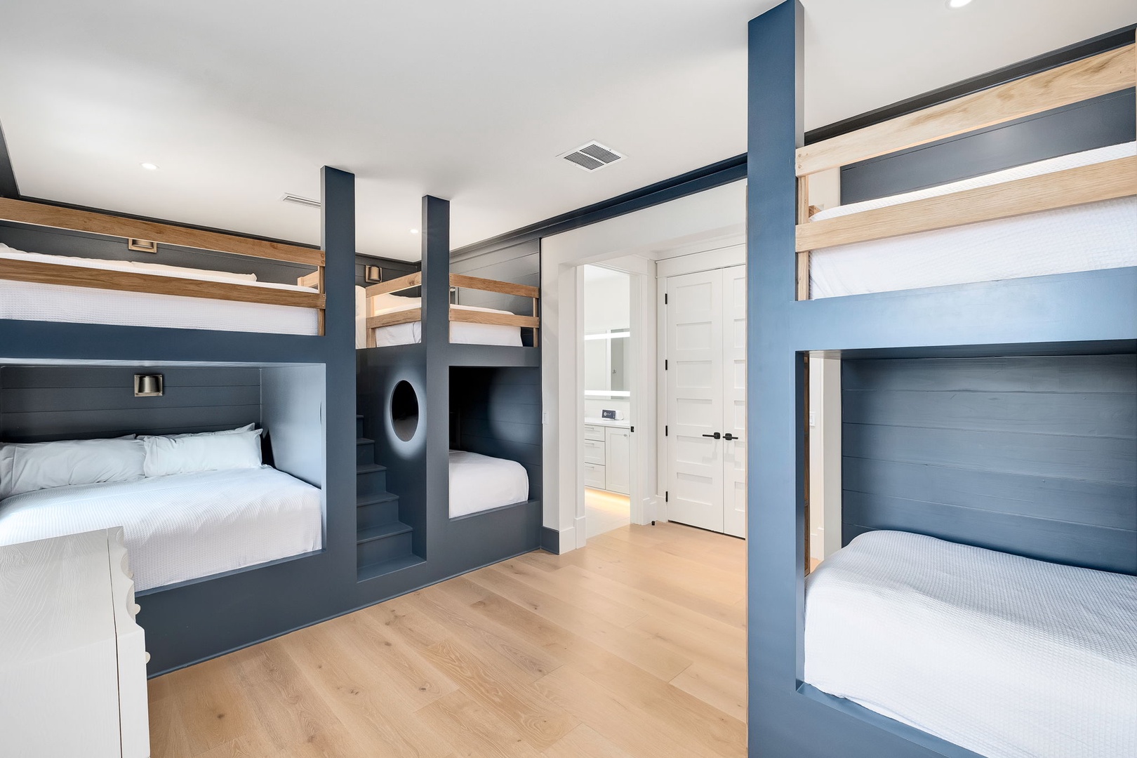 Your group will love this thoughtfully designed bunk room with custom-built sleeping spaces and crisp white linens. Nautical-inspired navy blue frames add character while ensuring everyone has their own cozy retreat.
