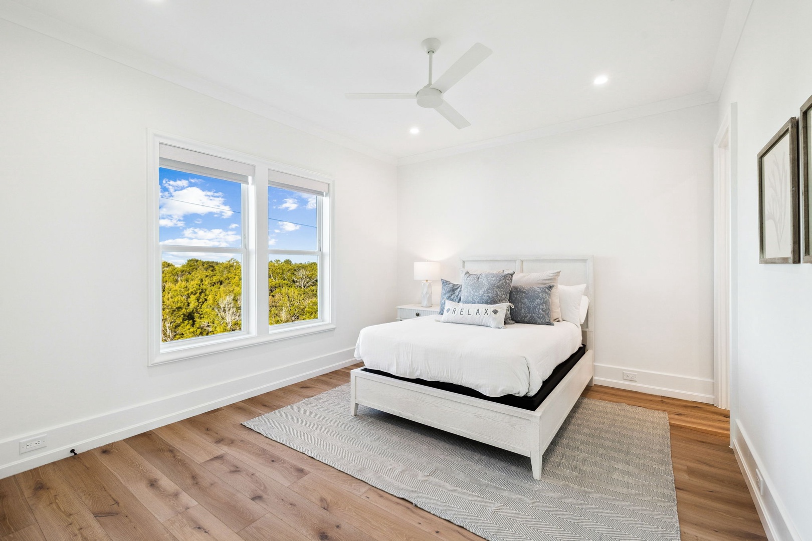 Wake up to peaceful treetop views in this bright, airy bedroom with crisp linens and natural light streaming through.