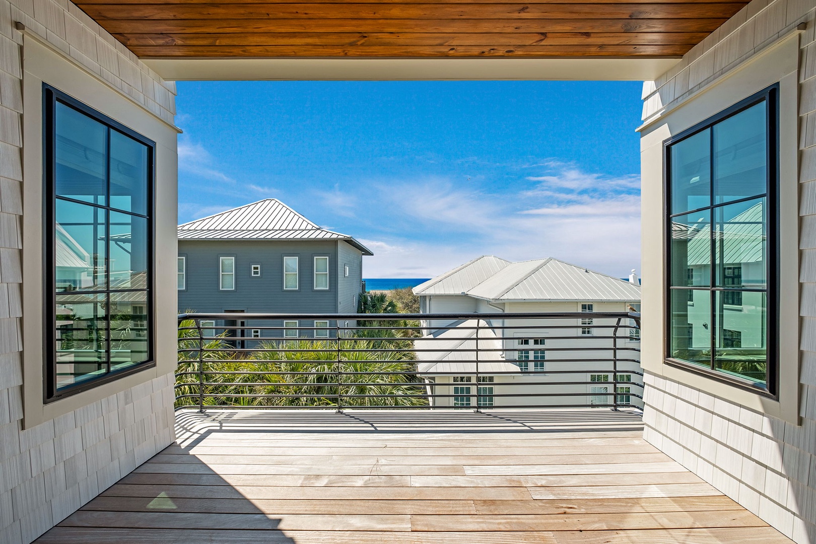 Step onto your private balcony where ocean breezes meet stunning views of coastal homes and sparkling blue waters beyond.
