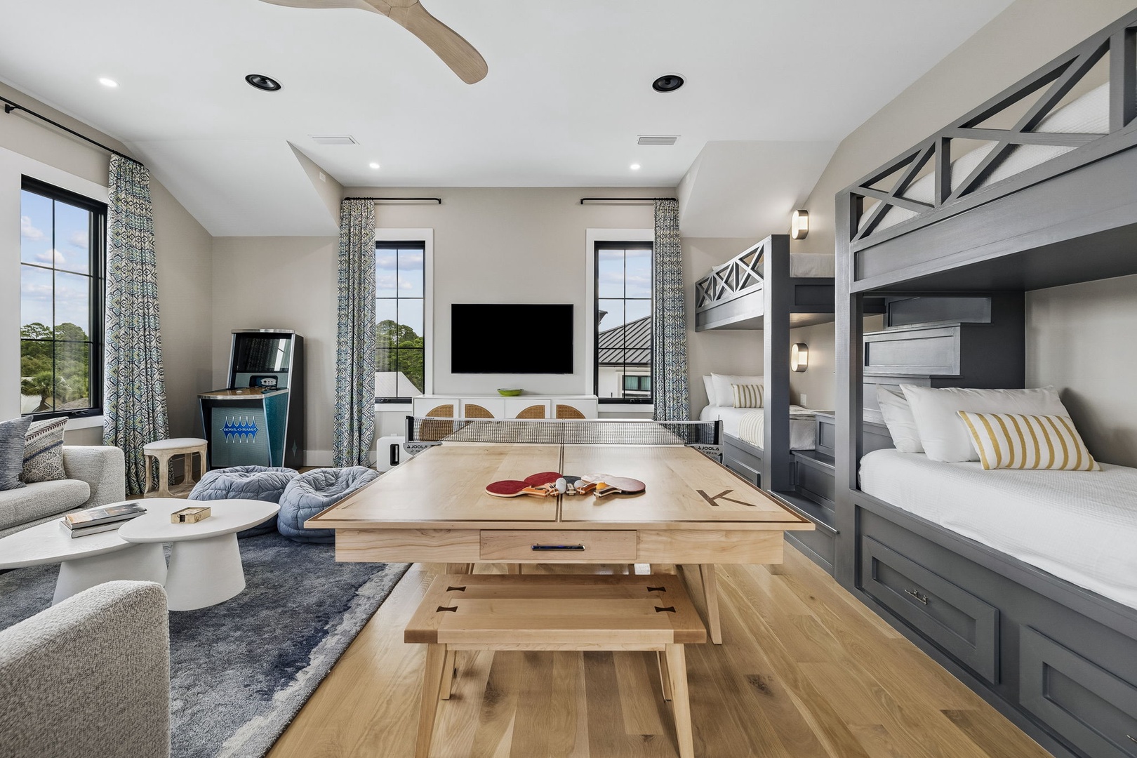 Your open-concept space blends relaxation and play, with custom bunk beds for the kids, cozy seating, a game table for family fun, and large windows framing peaceful views.