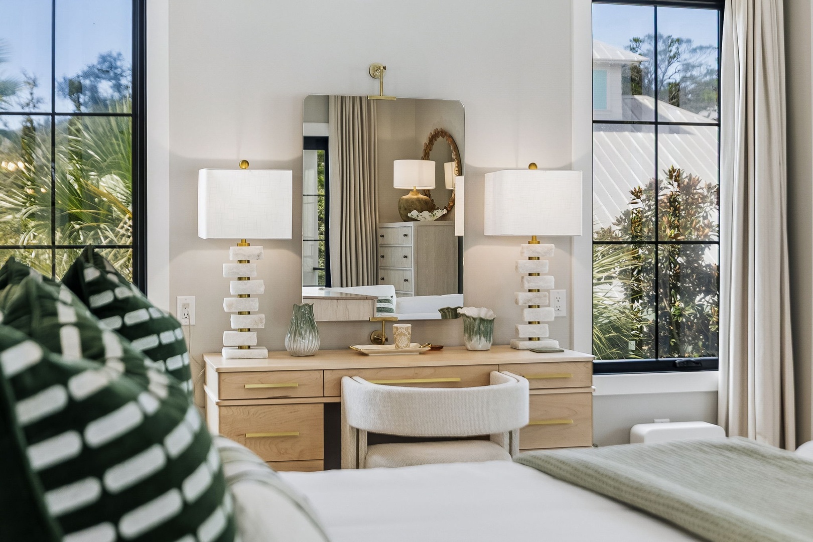 Your elegantly appointed bedroom invites calm with soft natural light, a chic vanity perfect for morning rituals, and lush garden views framing two oversized windows.