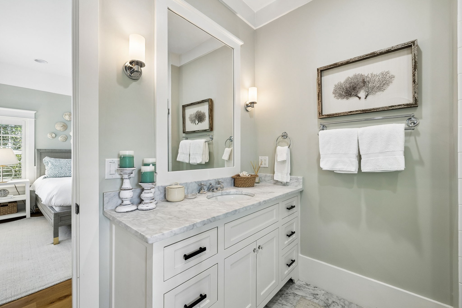 Your private bathroom feels like a serene spa retreat with calming coastal tones, marble countertops, and plush white towels awaiting you after a refreshing shower.