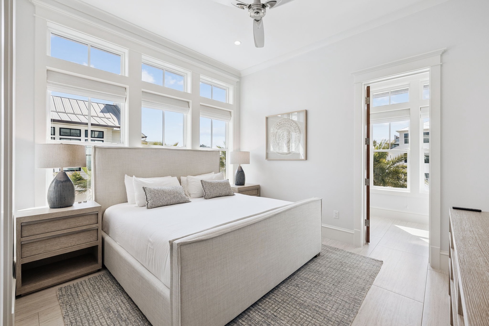 Drift off in your serene bedroom sanctuary with crisp linens and gentle ceiling fan. Natural light fills the space through tall windows.