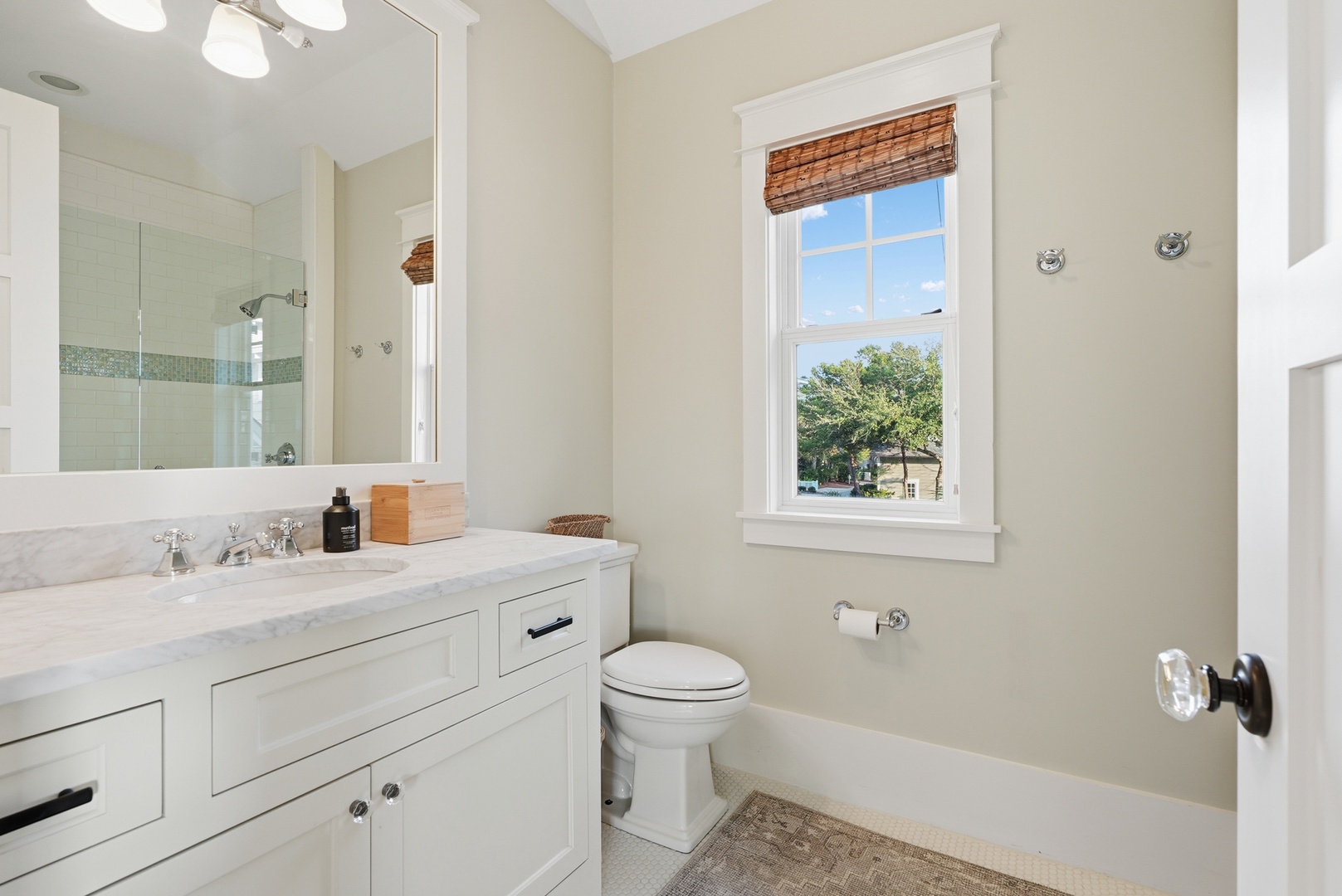 Step into a bright, freshly updated bathroom with classic white cabinetry, marble countertops, and a soothing tile shower—your personal retreat after a day of exploring nearby streets and greenery.