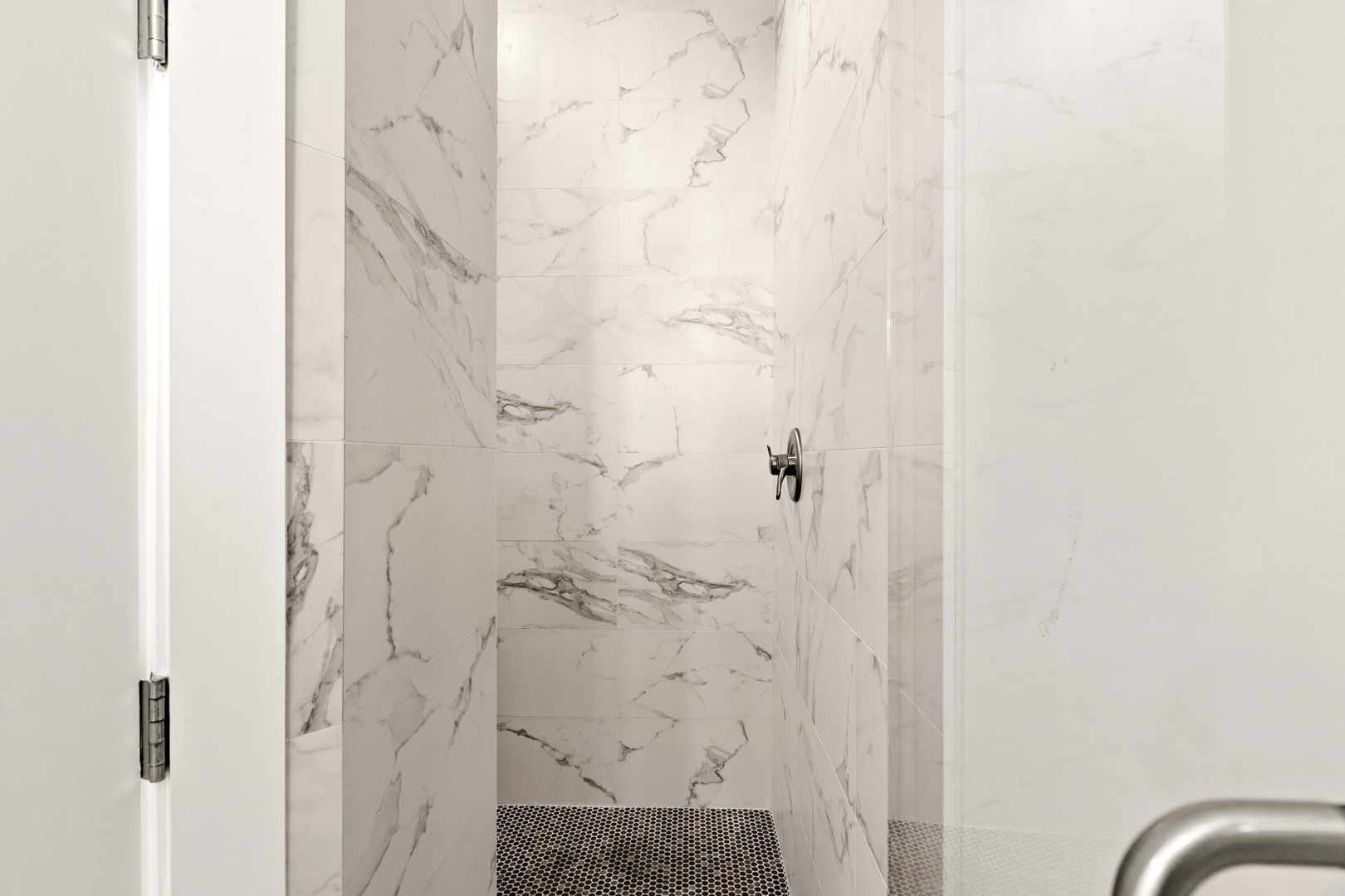 Luxurious marble-clad walk-in shower with elegant veining and modern fixtures invites you to unwind in style.