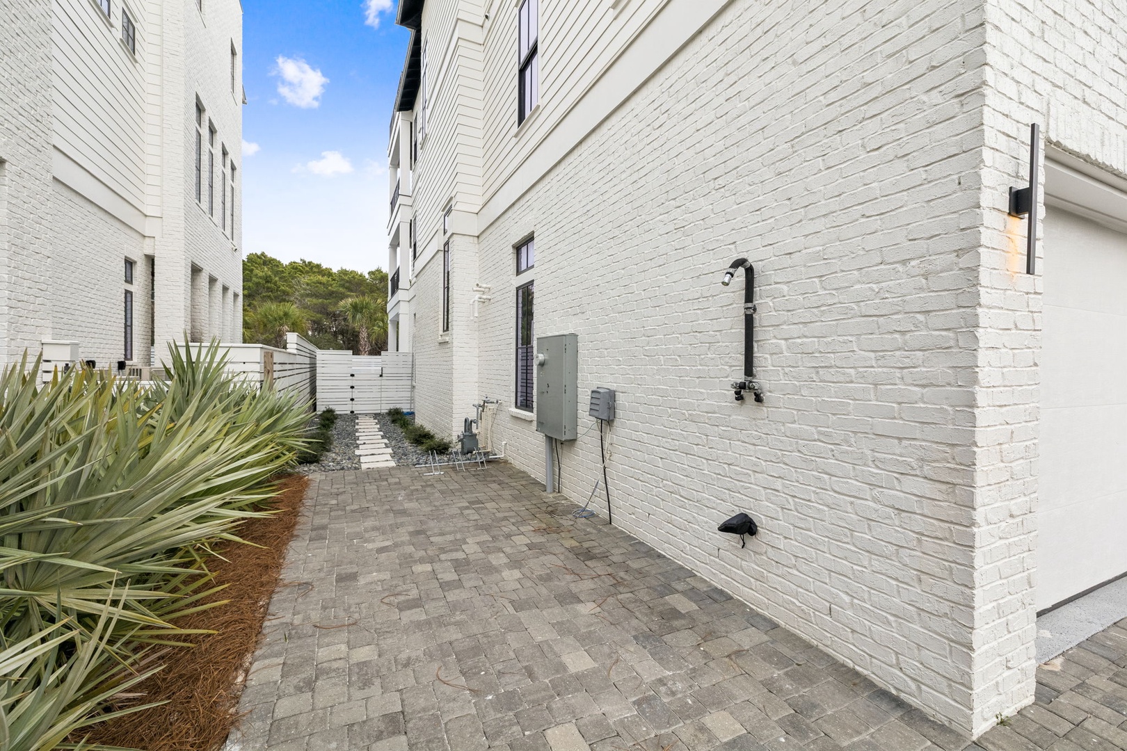 Modern white brick buildings frame this contemporary residential complex with landscaped courtyards and paved walkways.