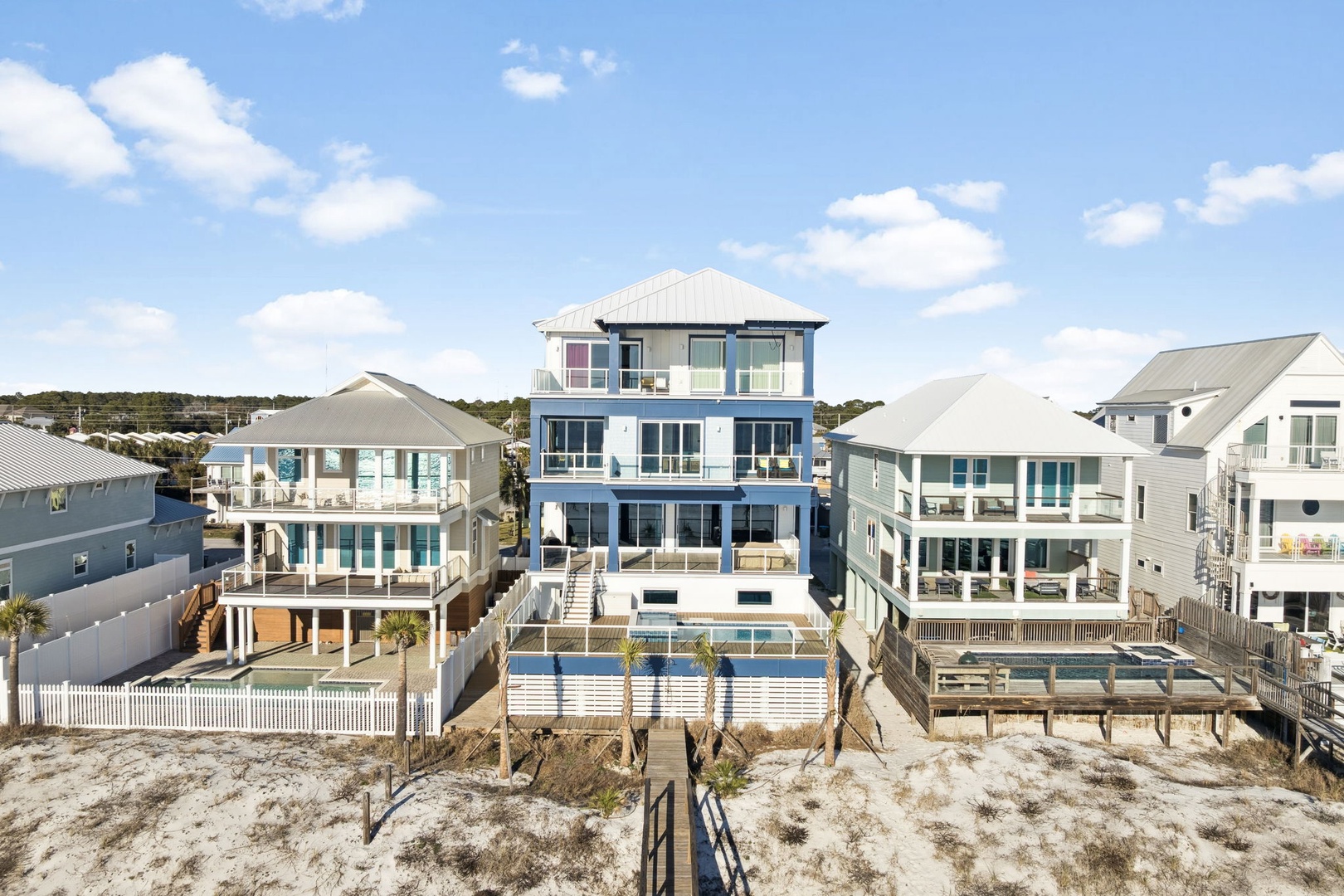 Stunning beachfront property featuring multiple levels with expansive decks and a private pool, surrounded by upscale coastal homes.