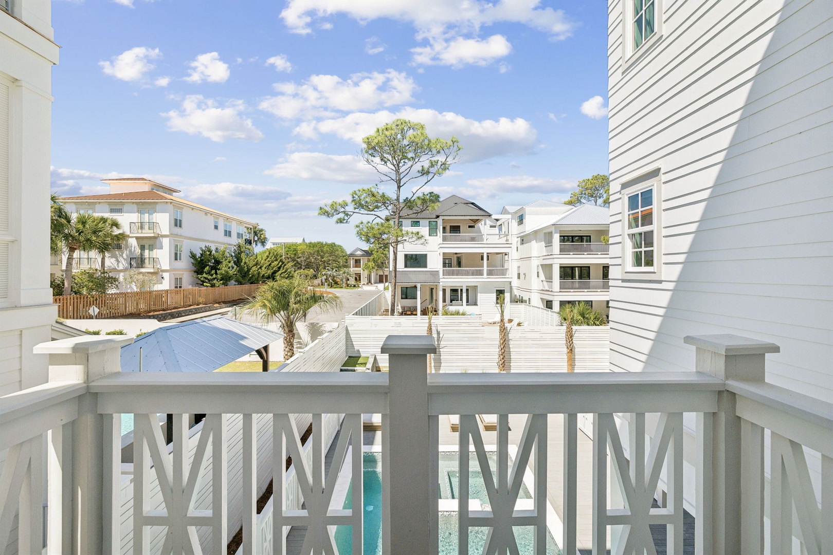 Expansive balcony view showcasing coastal homes and palm trees in a peaceful residential area.