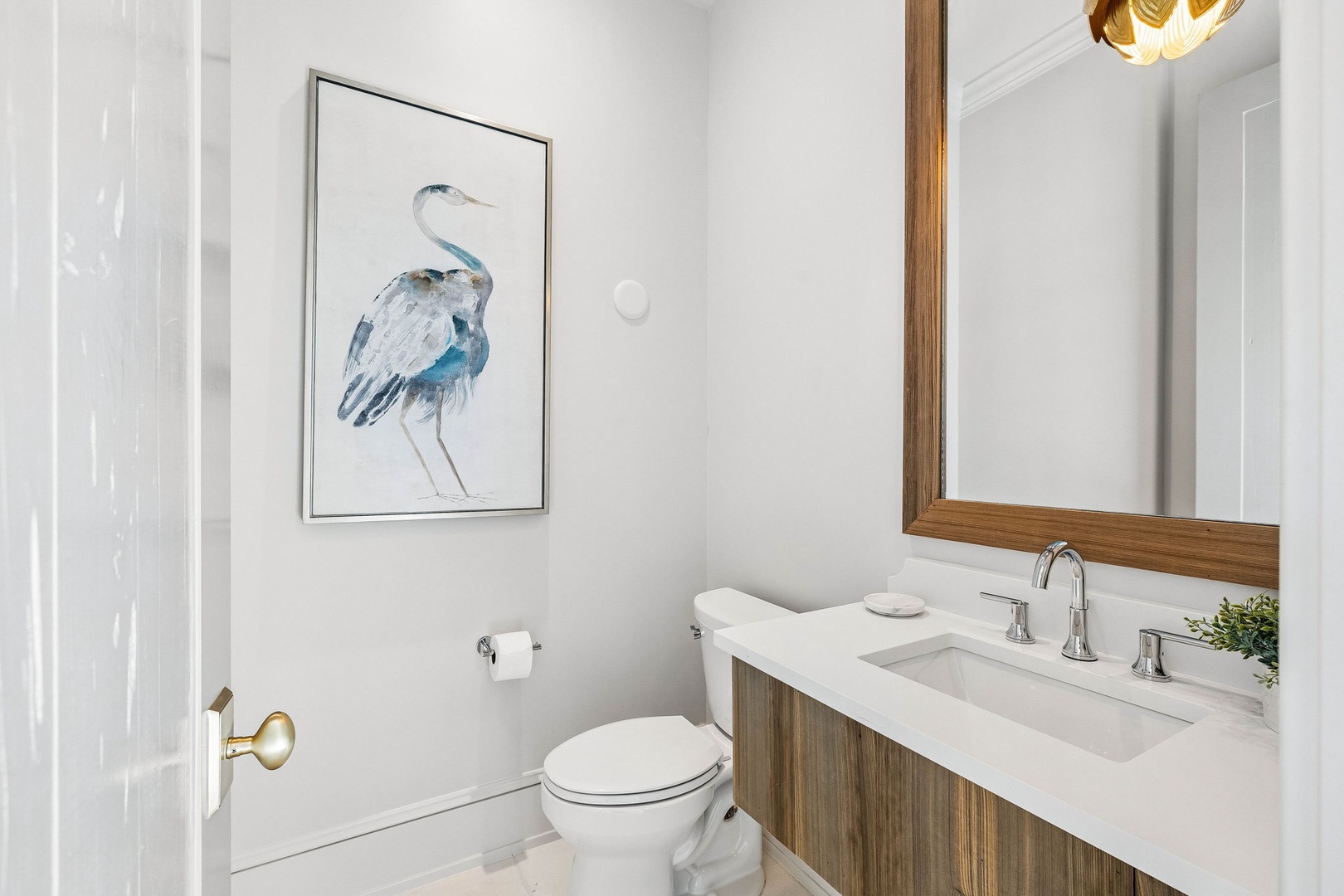 Step into your private bathroom featuring warm wood vanity, clean lines, and thoughtful coastal touches like the serene heron artwork that make your getaway feel both polished and personal.