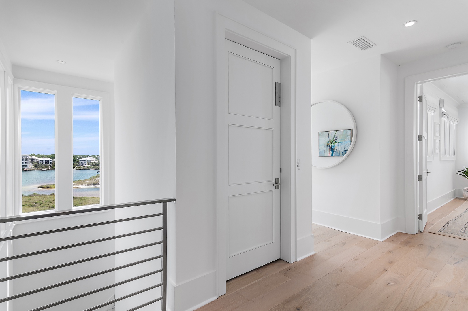 Wake up to stunning water views from your bright, airy hallway. Crisp white walls and warm wood floors create a peaceful retreat where every step feels like a breath of fresh air.