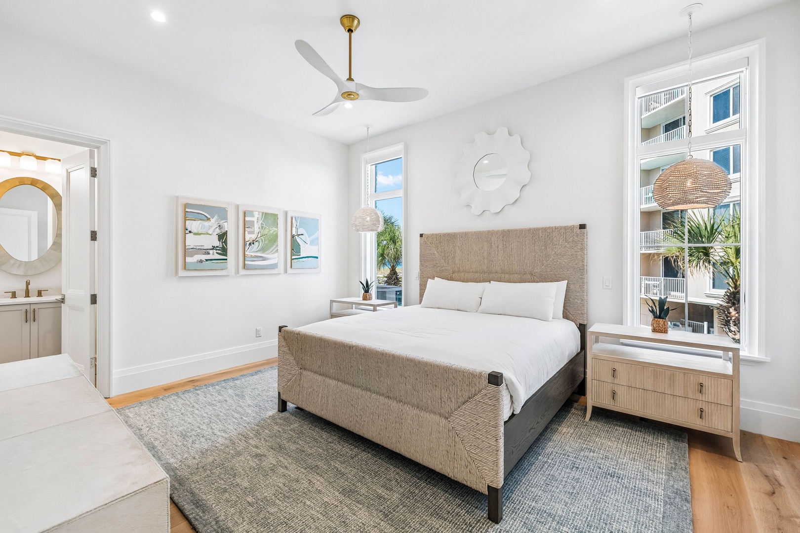 Drift off in your serene coastal retreat, where soft linens, natural textures, and gentle breezes from the ceiling fan create the perfect escape. Wake to sunlight streaming through tall windows and the promise of relaxation ahead.