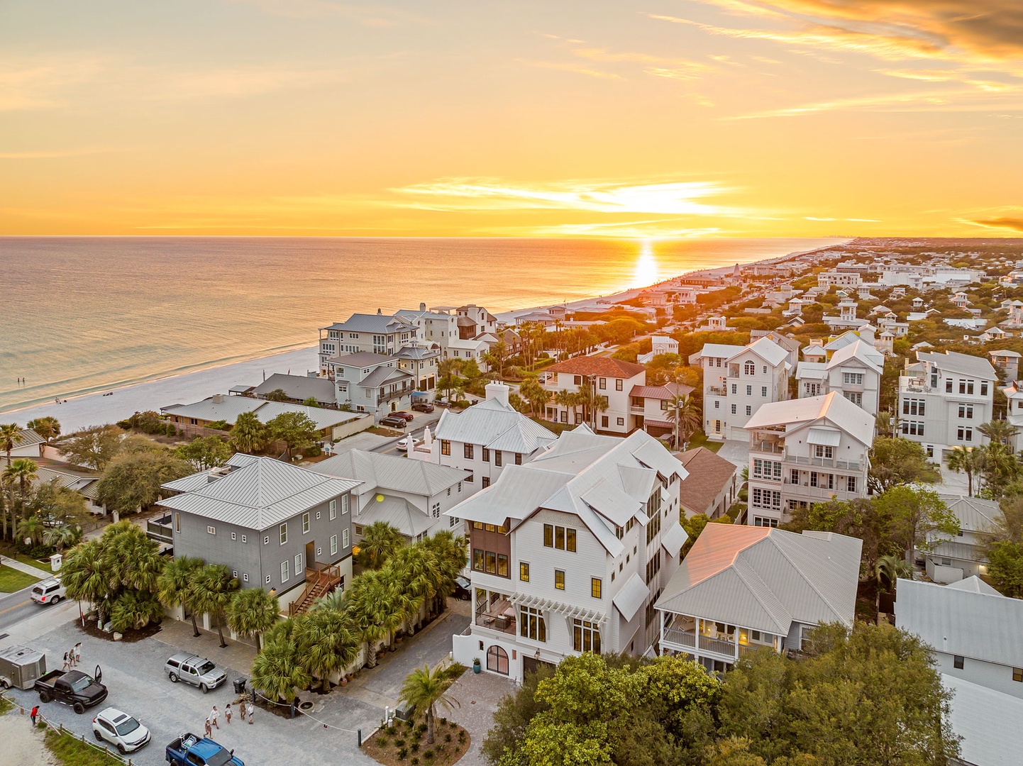 Golden sunset illuminates this charming coastal community, with pristine beaches and vacation homes stretching along the shoreline.