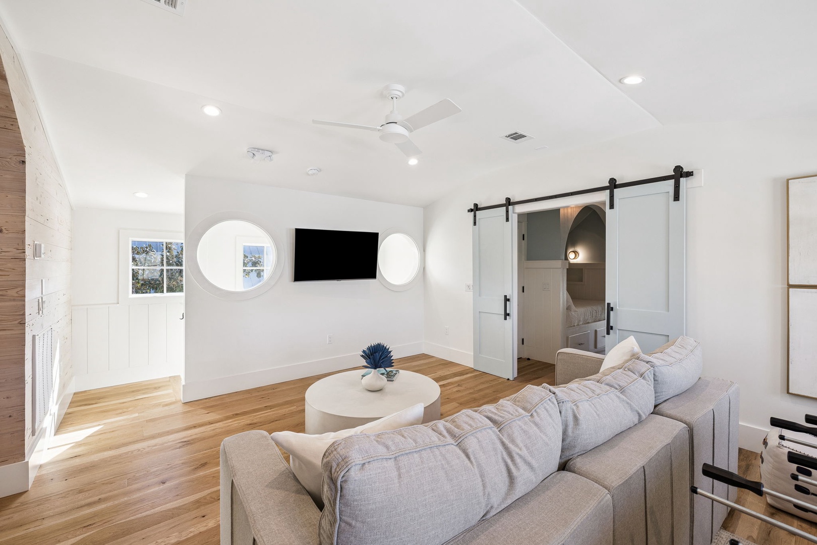 Relax in your bright, modern living space with soaring ceilings, cozy sectional seating, and stylish barn doors leading to private quarters.