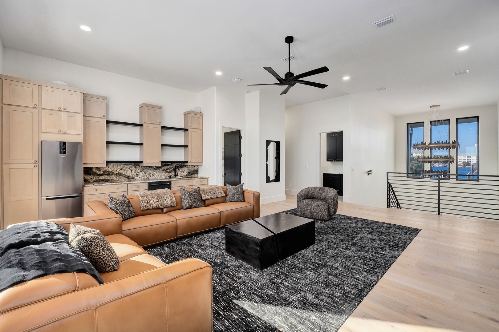 Relax in your spacious open-concept living area with luxurious leather seating, modern kitchen, and stunning city views from floor-to-ceiling windows.