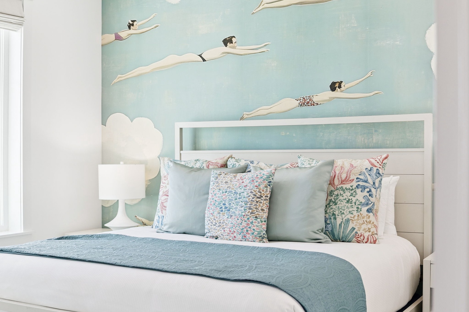 Drift off to sleep beneath a dreamy mural of swimmers gliding through soft blue skies on pillowy clouds.