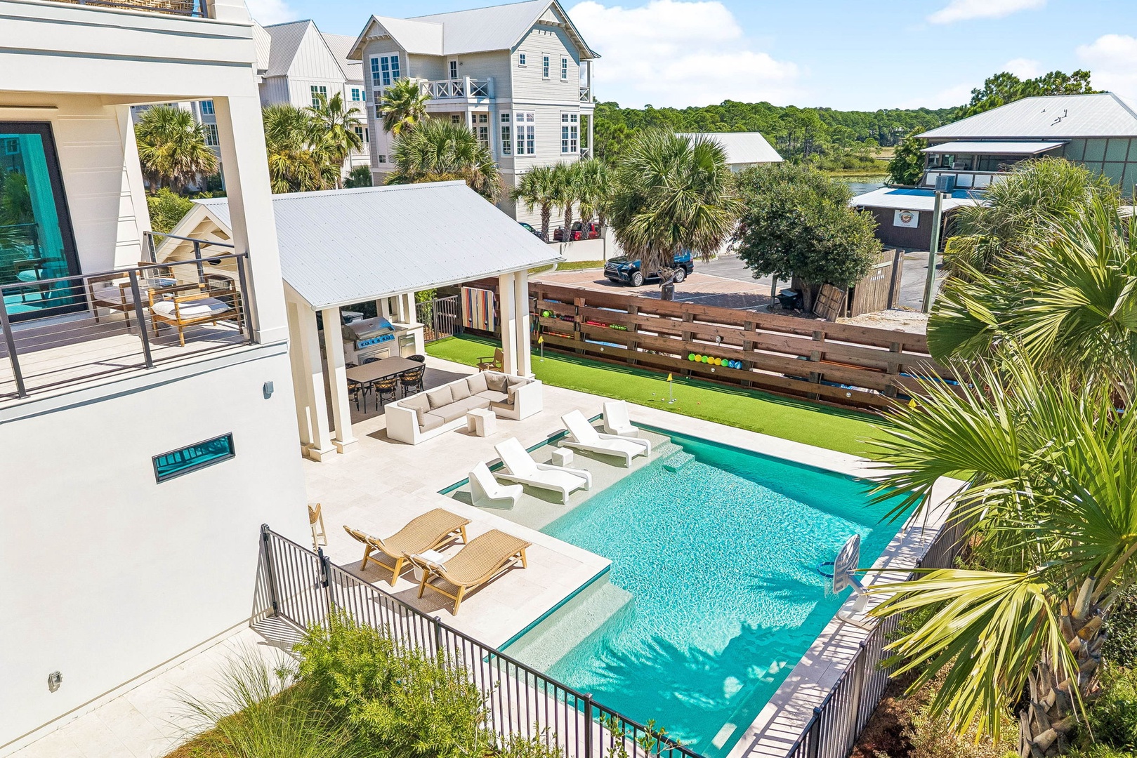 Coastal modern retreat with private pool, covered outdoor lounge, and lush lawn—perfect for sun-soaked afternoons and poolside relaxation in a serene, palm-shaded setting.