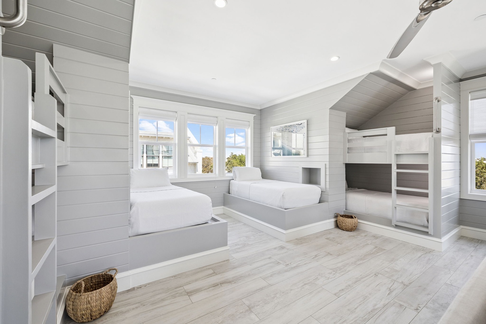 Unwind in your serene coastal bunk room featuring custom-built beds, soft linens, and natural light streaming through windows.